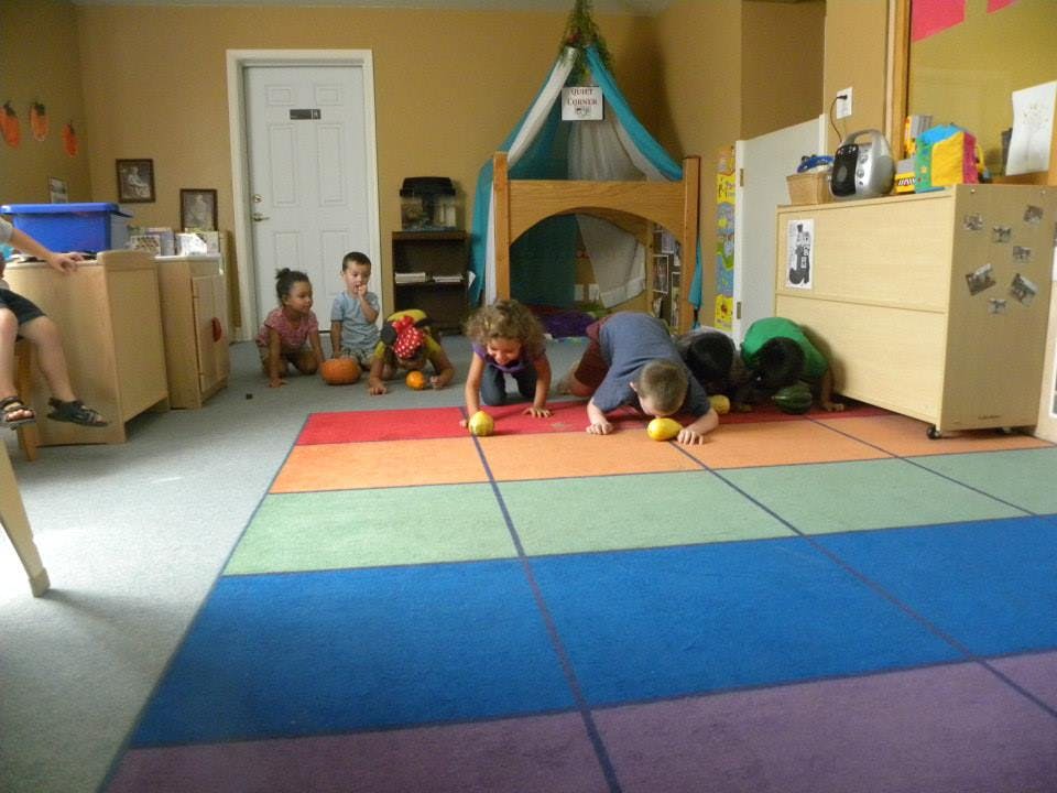 Children playing on a colorful mat in a classroom