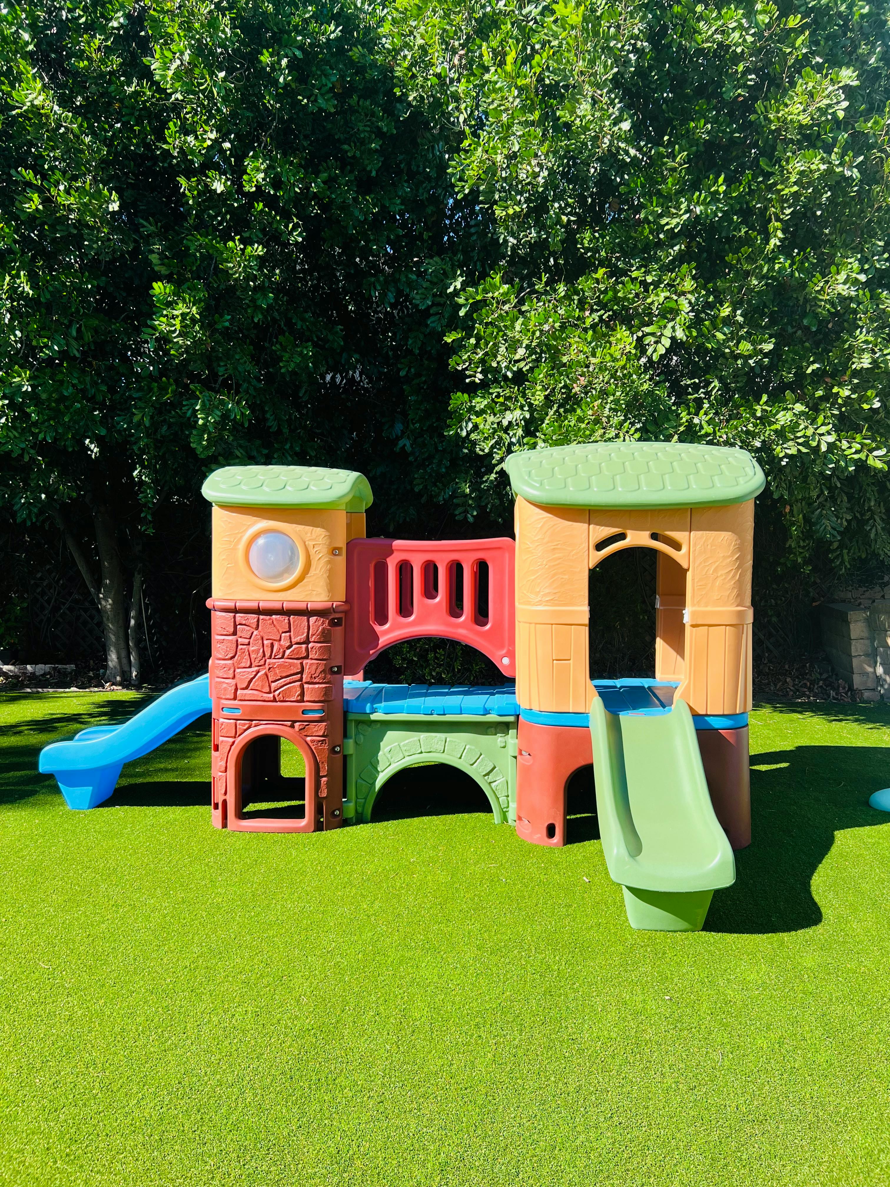 Colorful plastic playground structure with slides on green turf