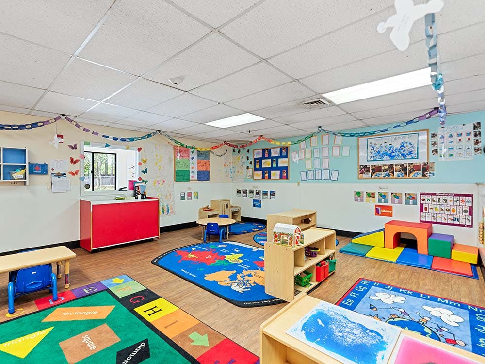 Colorful playroom with rugs, child-sized tables, and learning materials