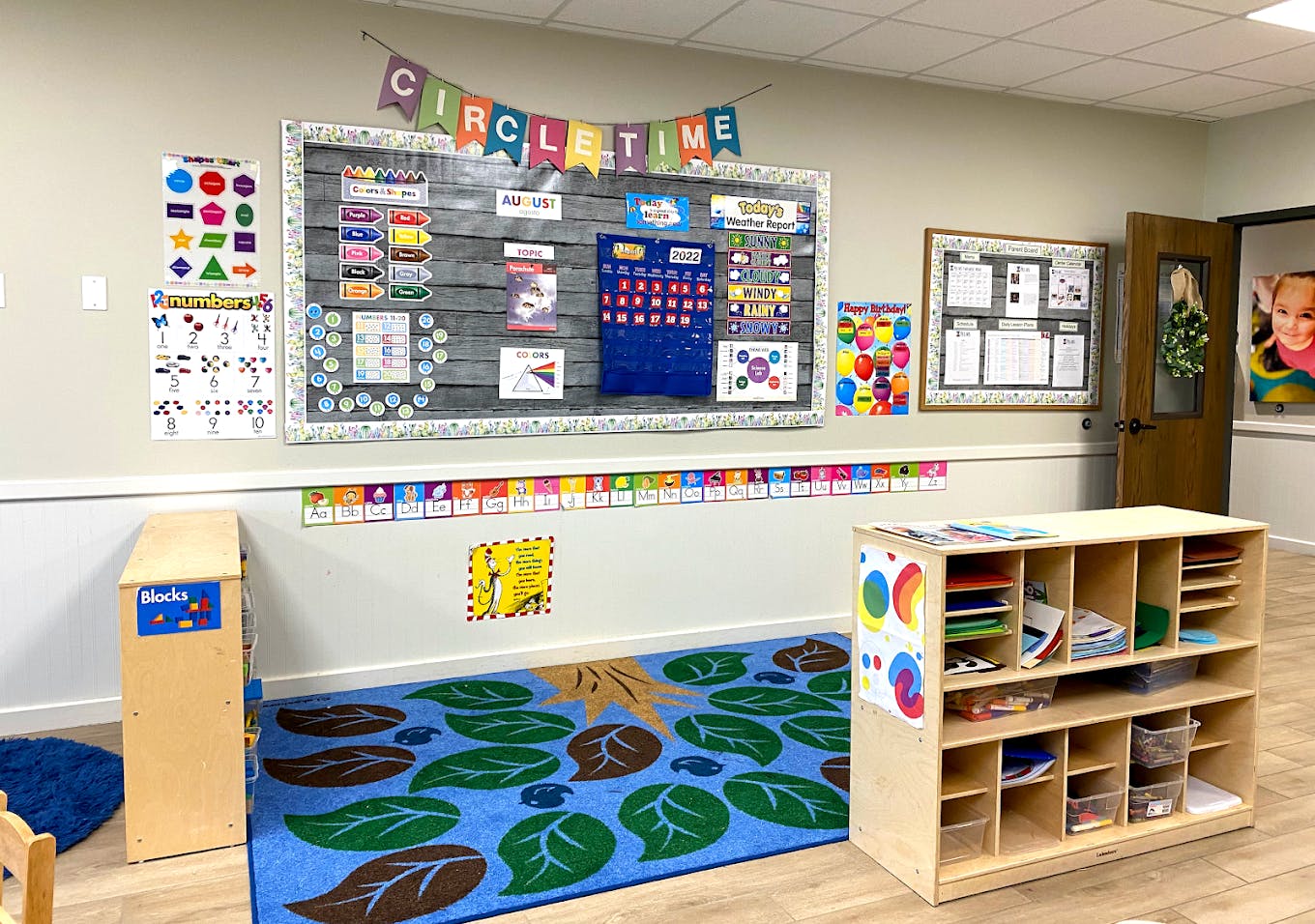 Classroom interior with educational posters and a play area rug