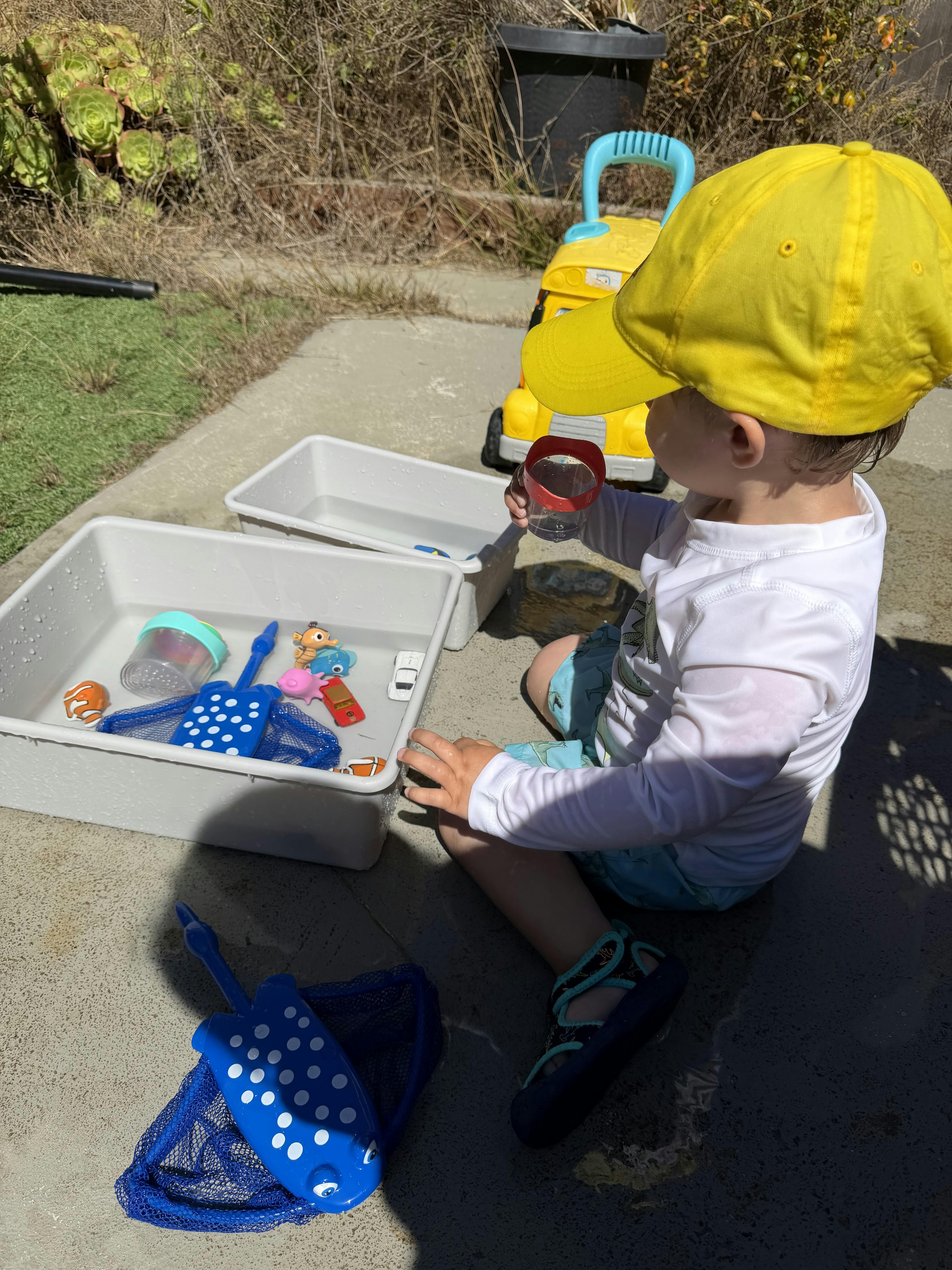 Child playing with water bins and toys outdoors
