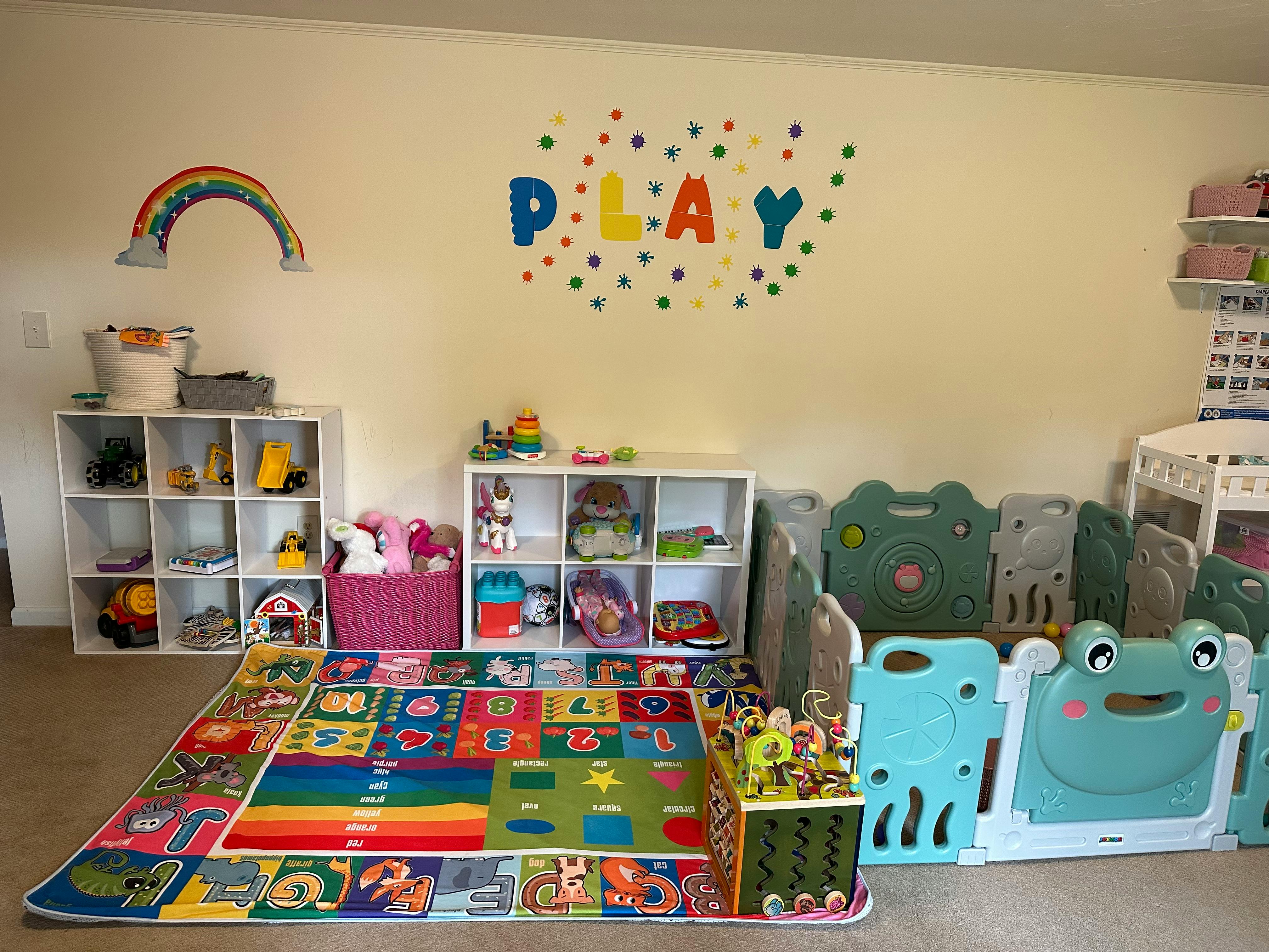 Playroom with colorful rug, toy shelves, and playpen