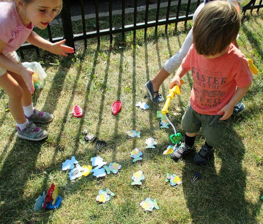 Two children playing a fishing game on grass