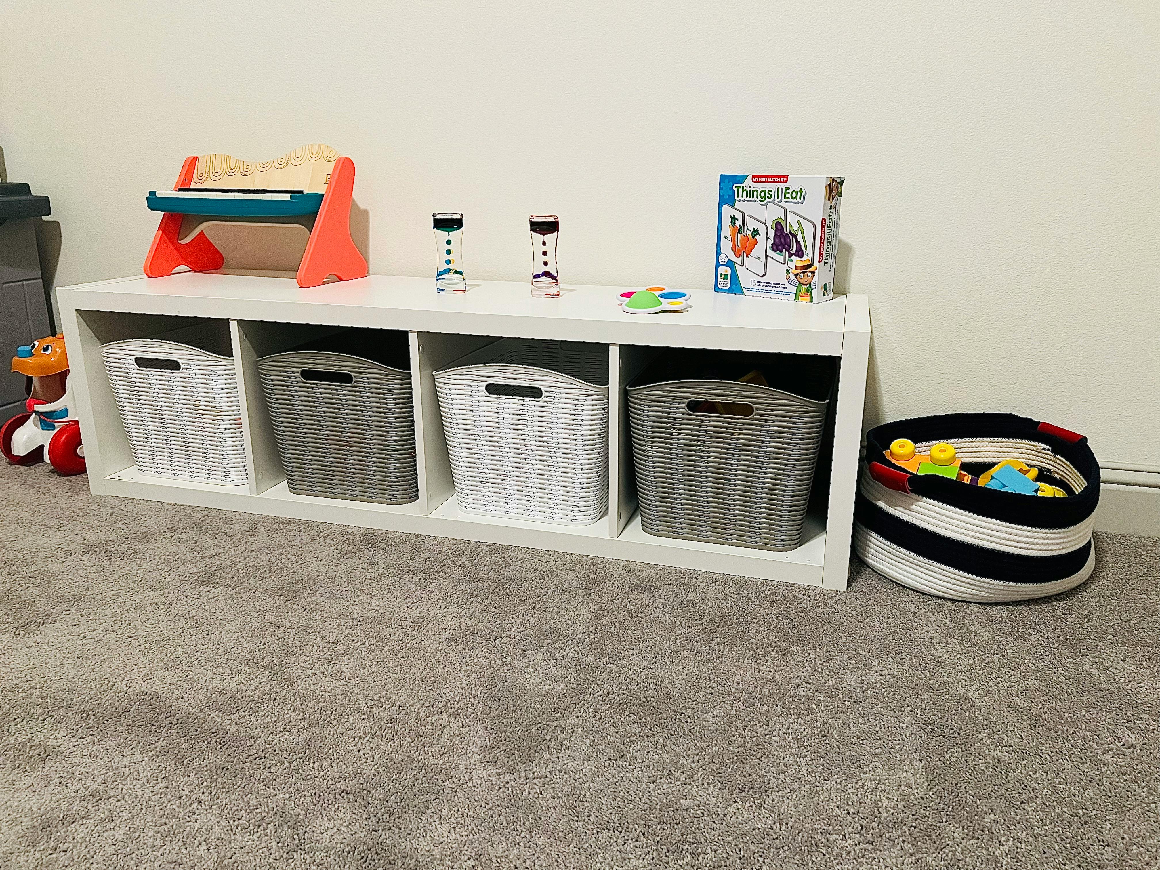 White storage unit with baskets and toys on a carpeted floor