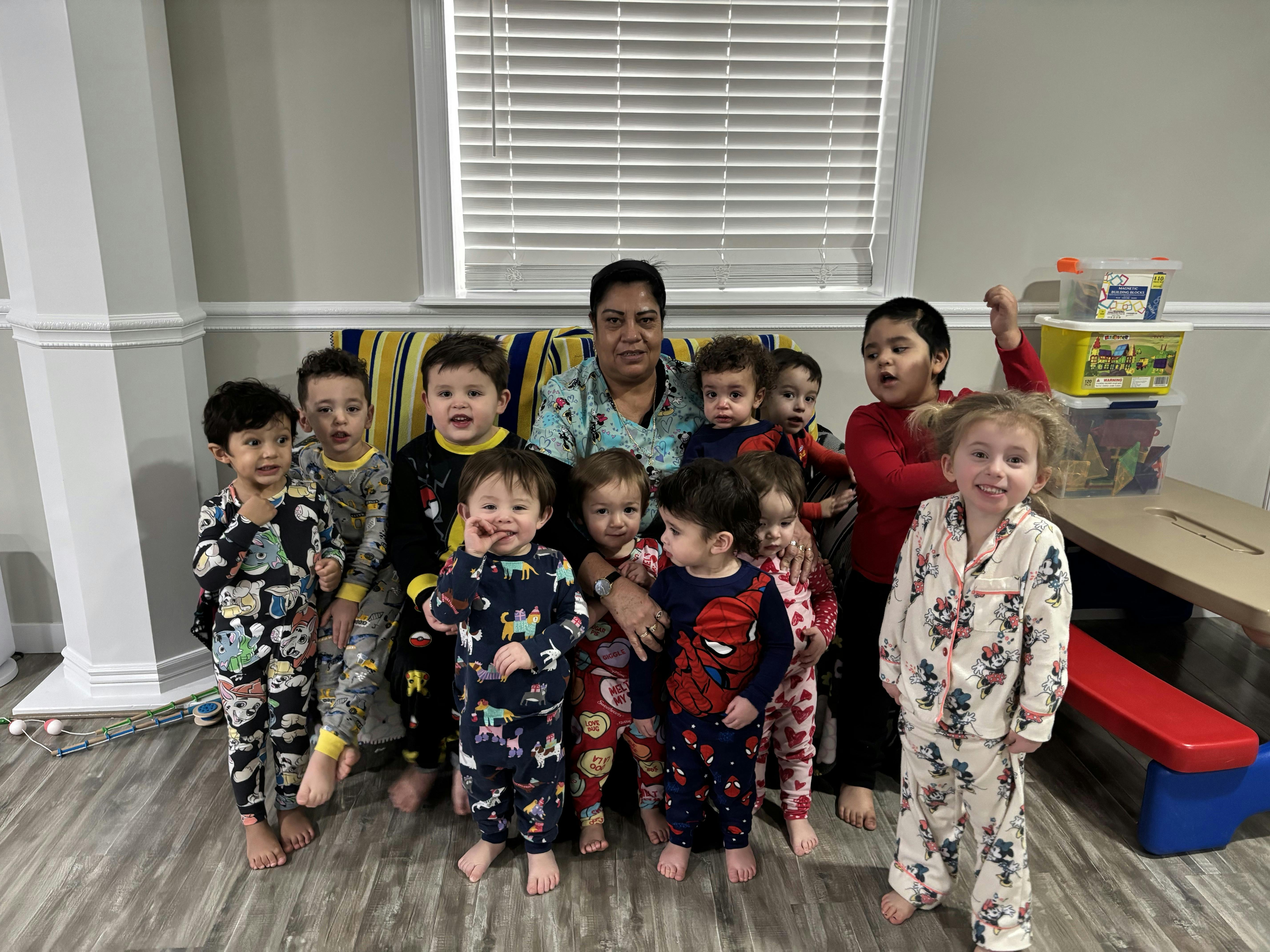 Person sitting on a couch surrounded by multiple children in pajamas