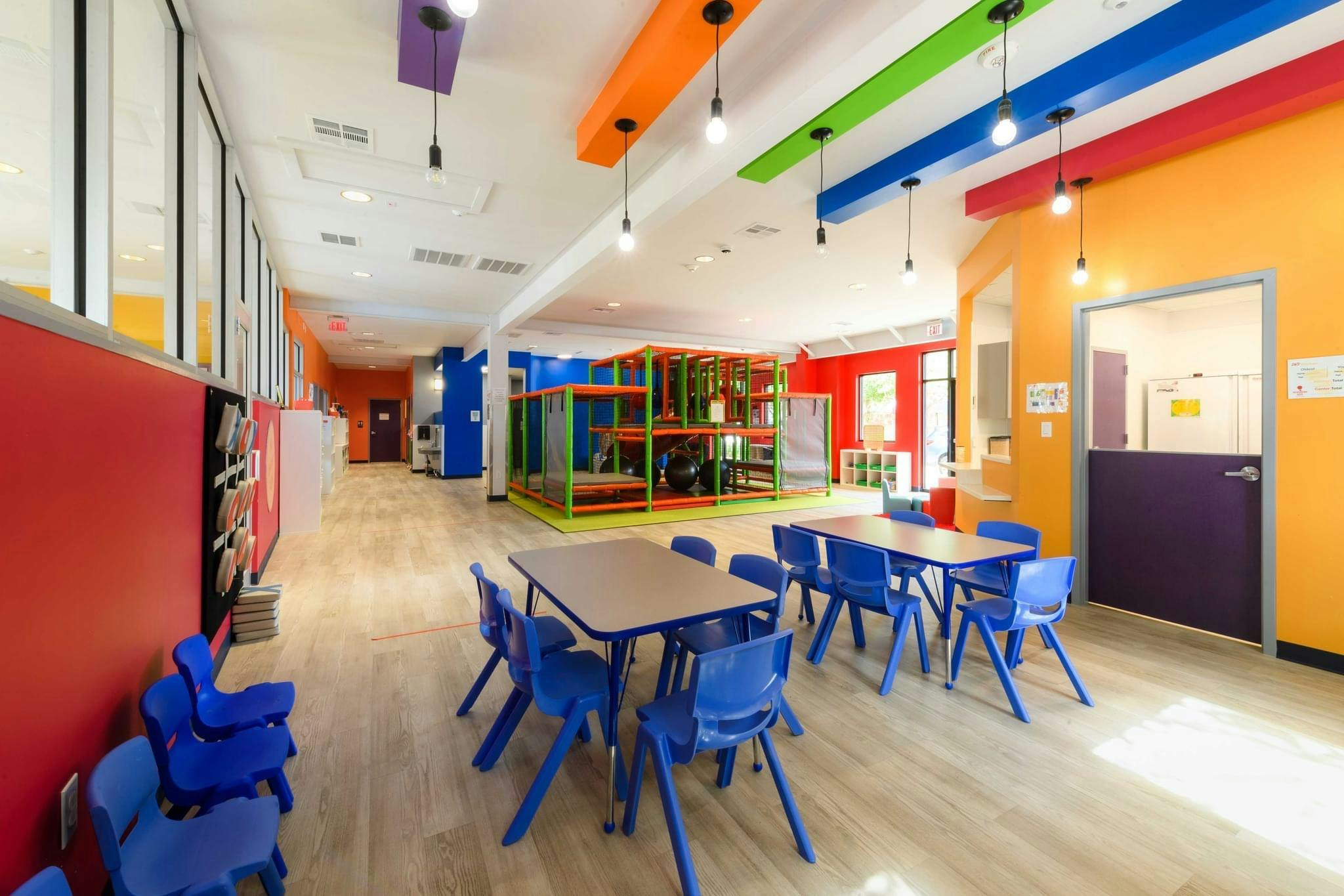 Playroom with tables and chairs, colorful walls, and indoor play structure