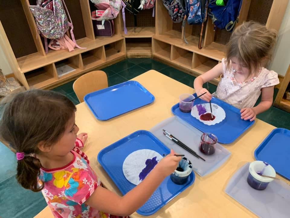 Two children painting at a table in a classroom