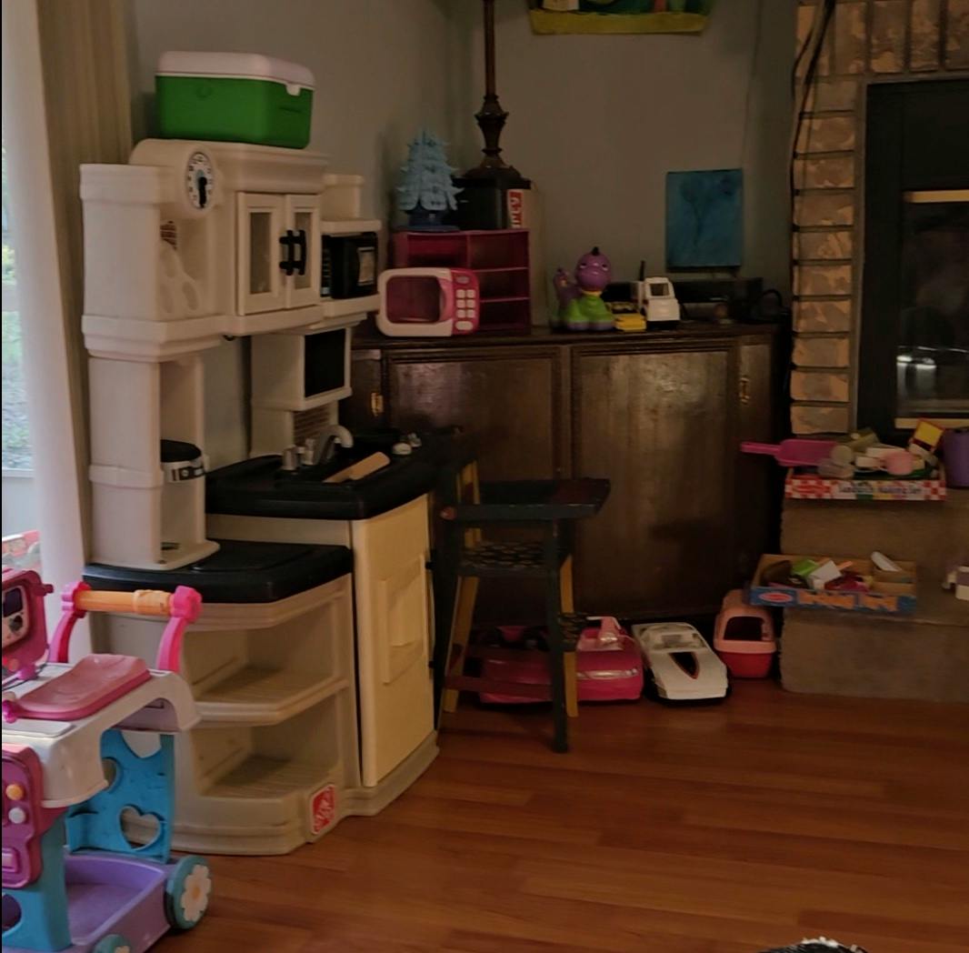 Toy kitchen set with various other toys scattered on the floor and furniture
