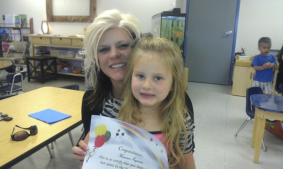 Person and child holding a certificate in a classroom