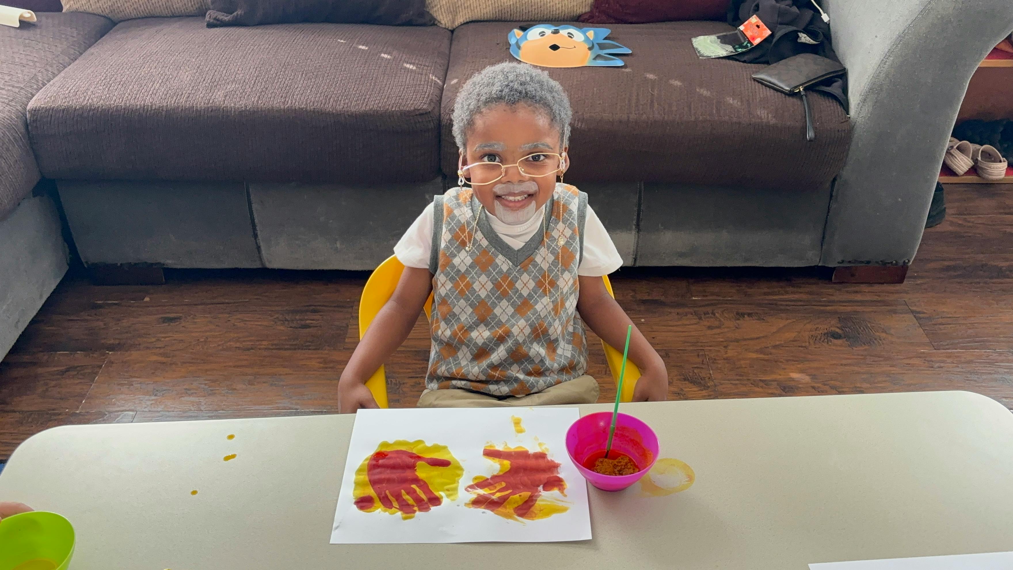 Child in glasses and sweater vest painting at a table