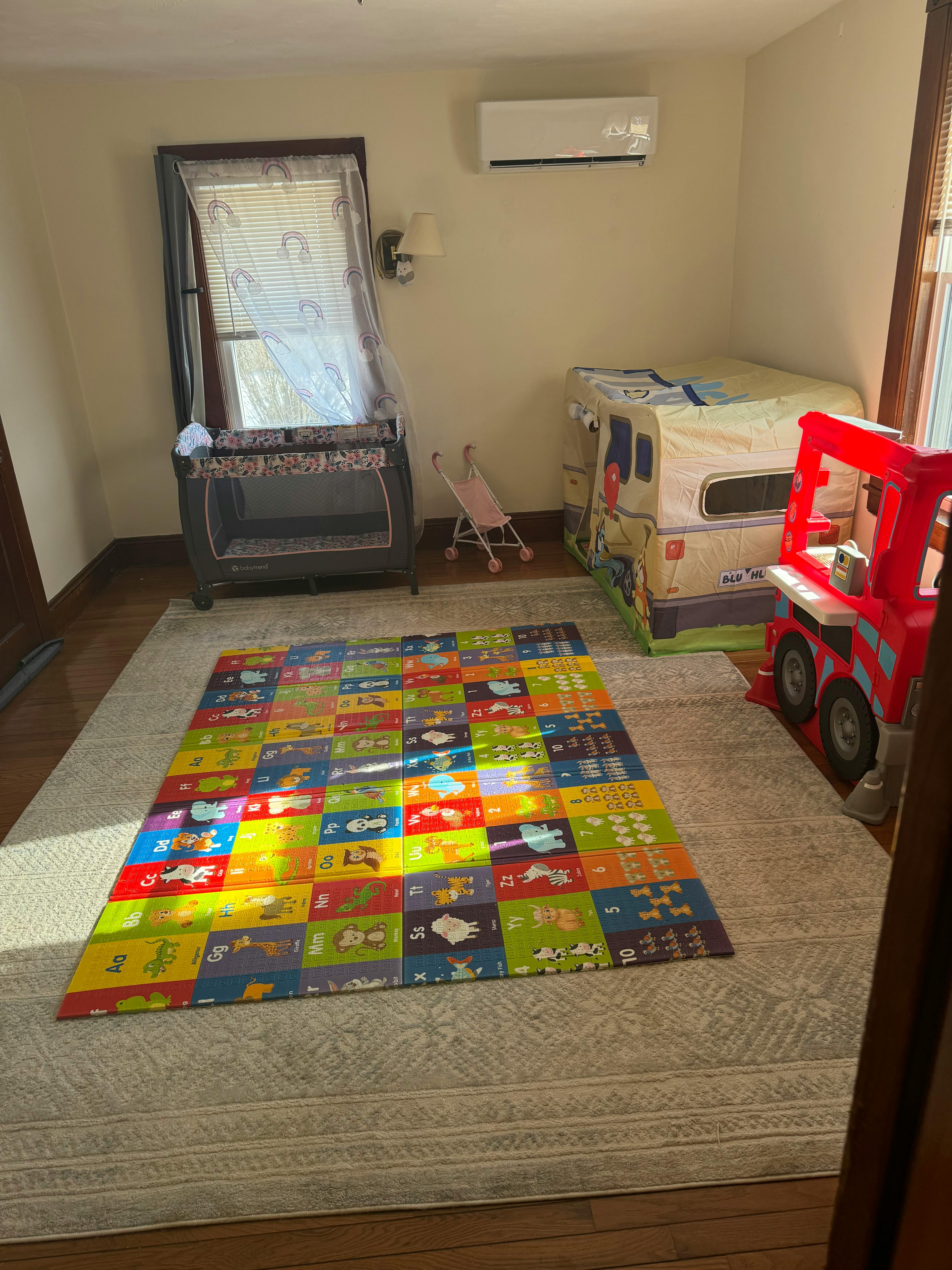 Playroom with a colorful playmat, crib, and toy truck