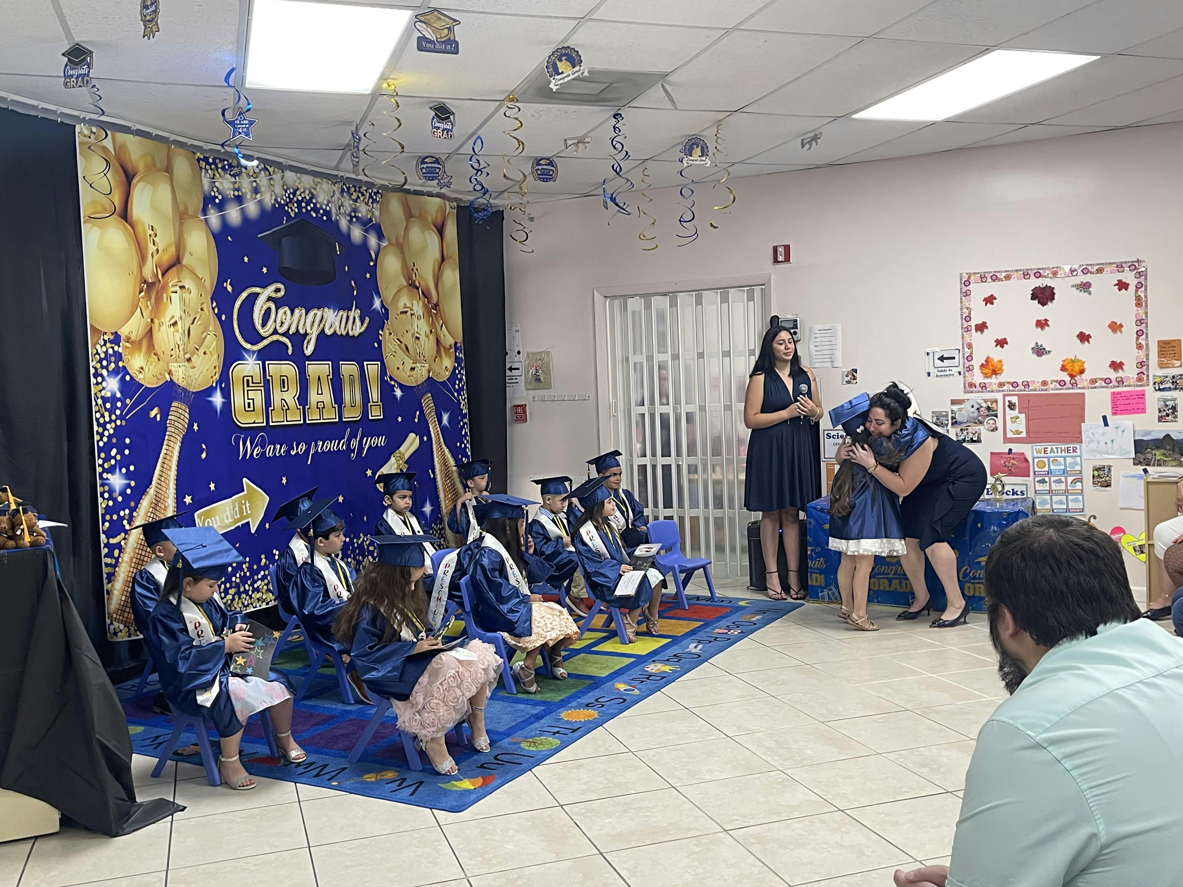 Adults and children in graduation caps and gowns at a ceremony