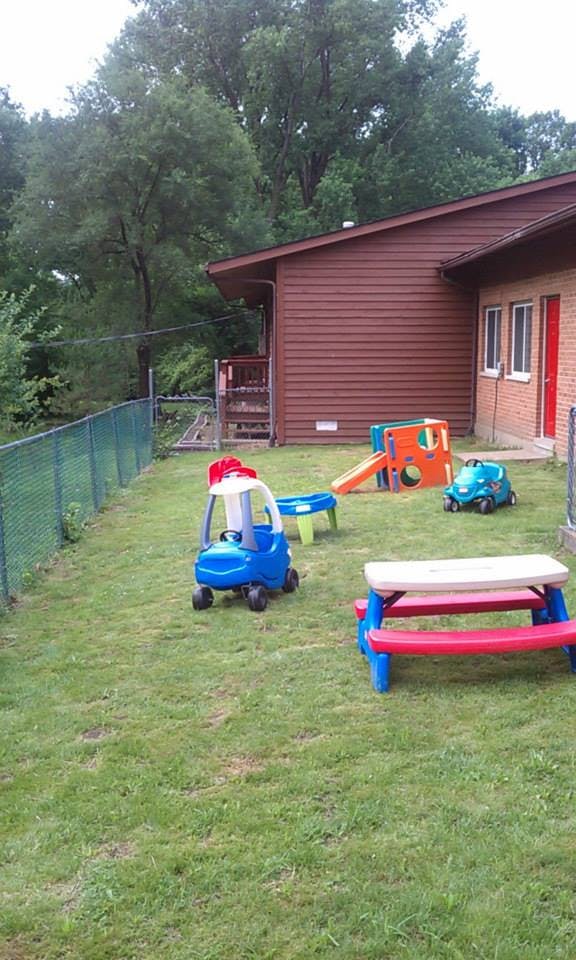 Outdoor play area with toy cars, a slide, and a picnic table on grass