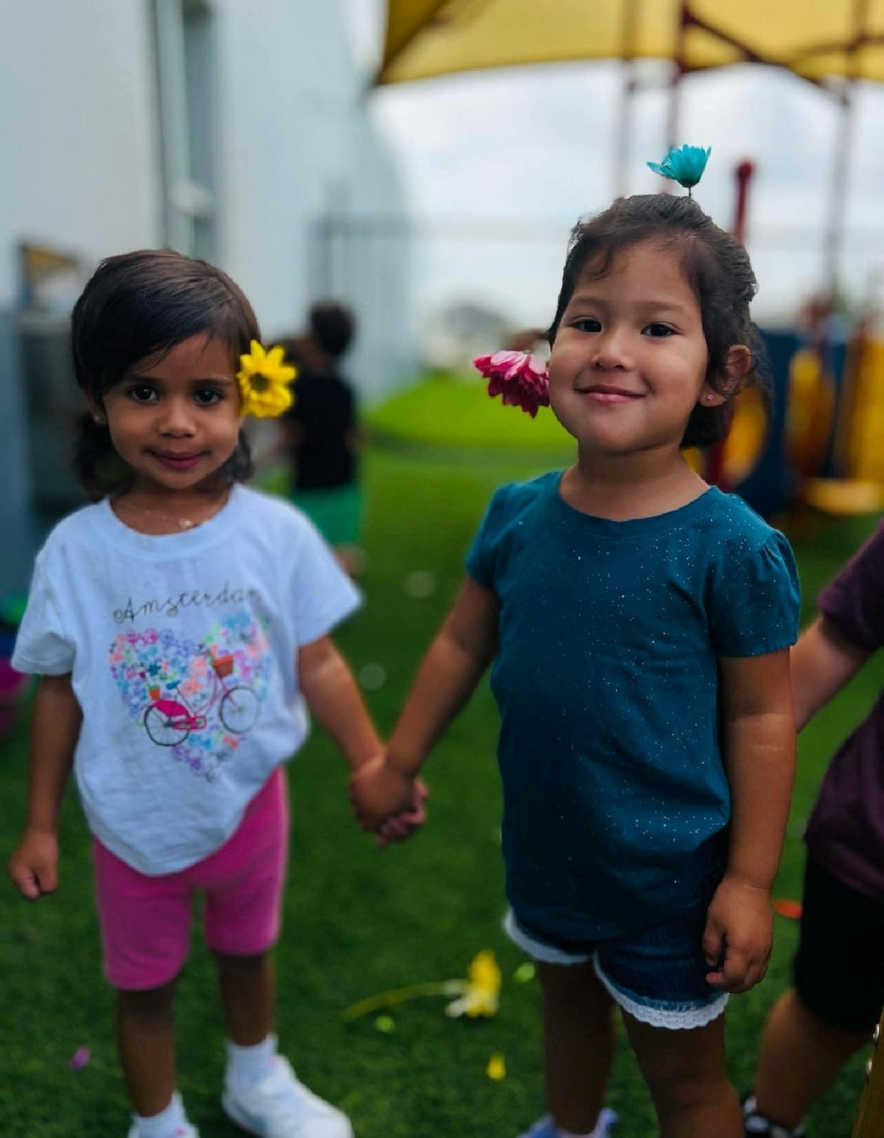 Two children holding hands with flowers in their hair