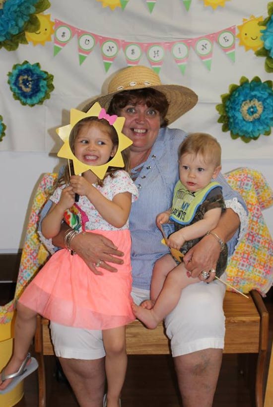 Person holding a child and a baby, child holding a sun-shaped cutout