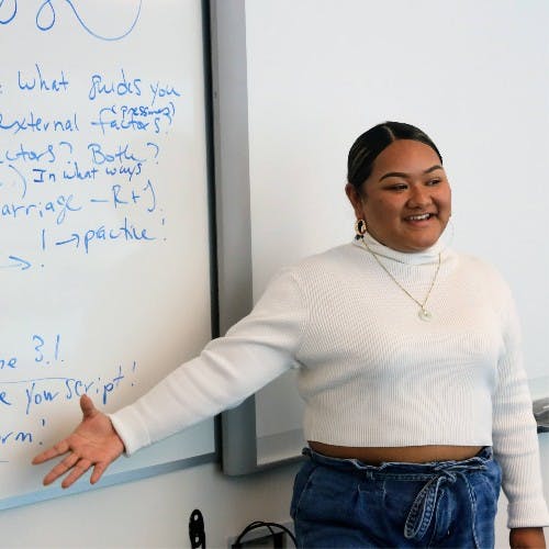 Person standing next to a whiteboard with writing, "What guides you" written on it