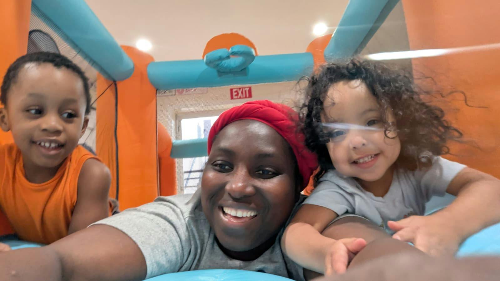 Adult and two children posing for a selfie in an inflatable bounce house