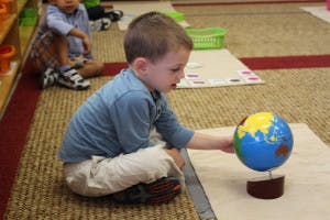 Child playing with a globe in a classroom