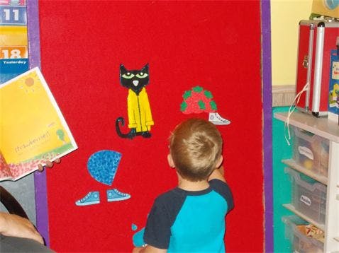 Child looking at felt board with cat and mushroom shapes