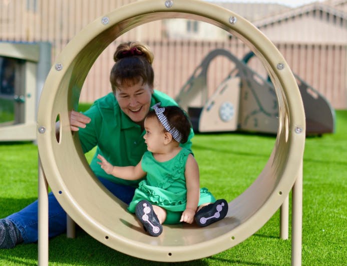 Person and child playing on a playground tunnel