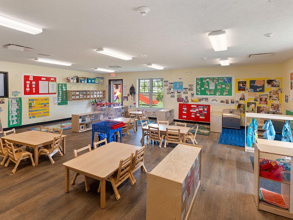 Empty classroom with small tables and chairs, and colorful decorations on the walls