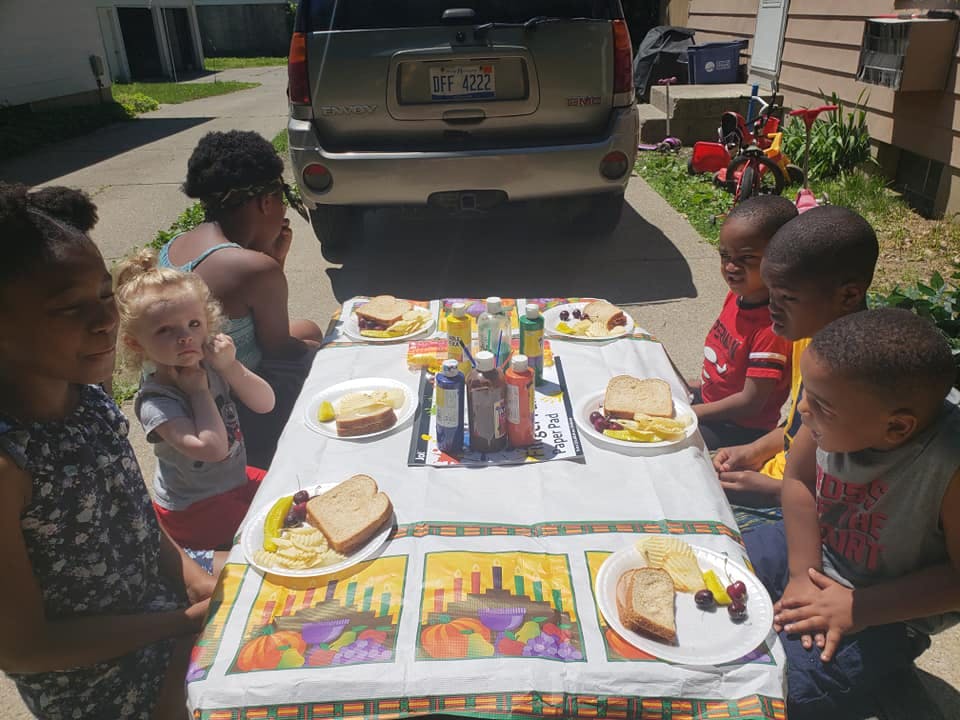 People and children sitting around a table with plates of food