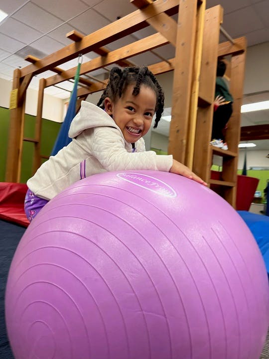 Child on a large purple exercise ball