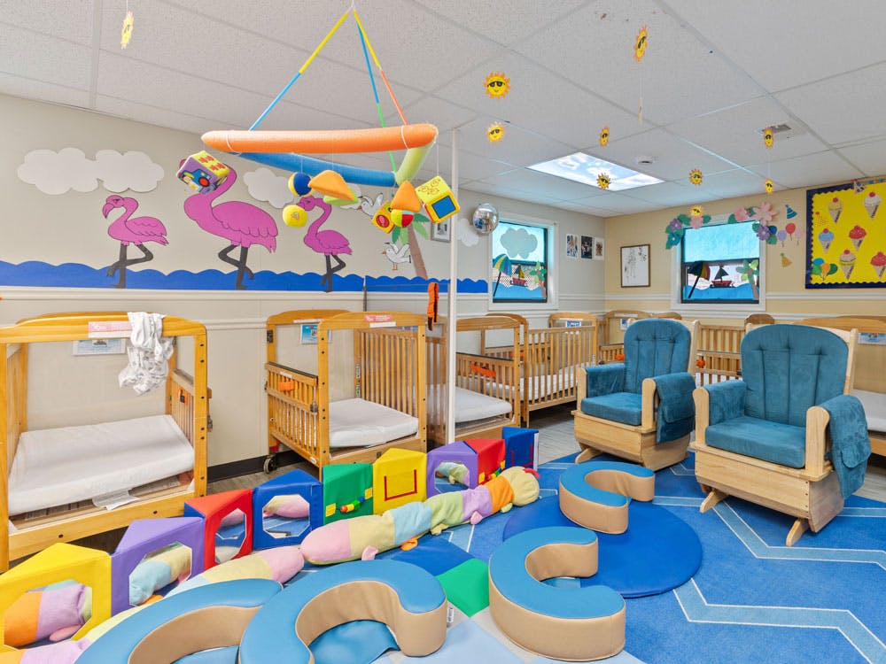Baby nursery room with cribs, rocking chairs, and colorful foam play toys