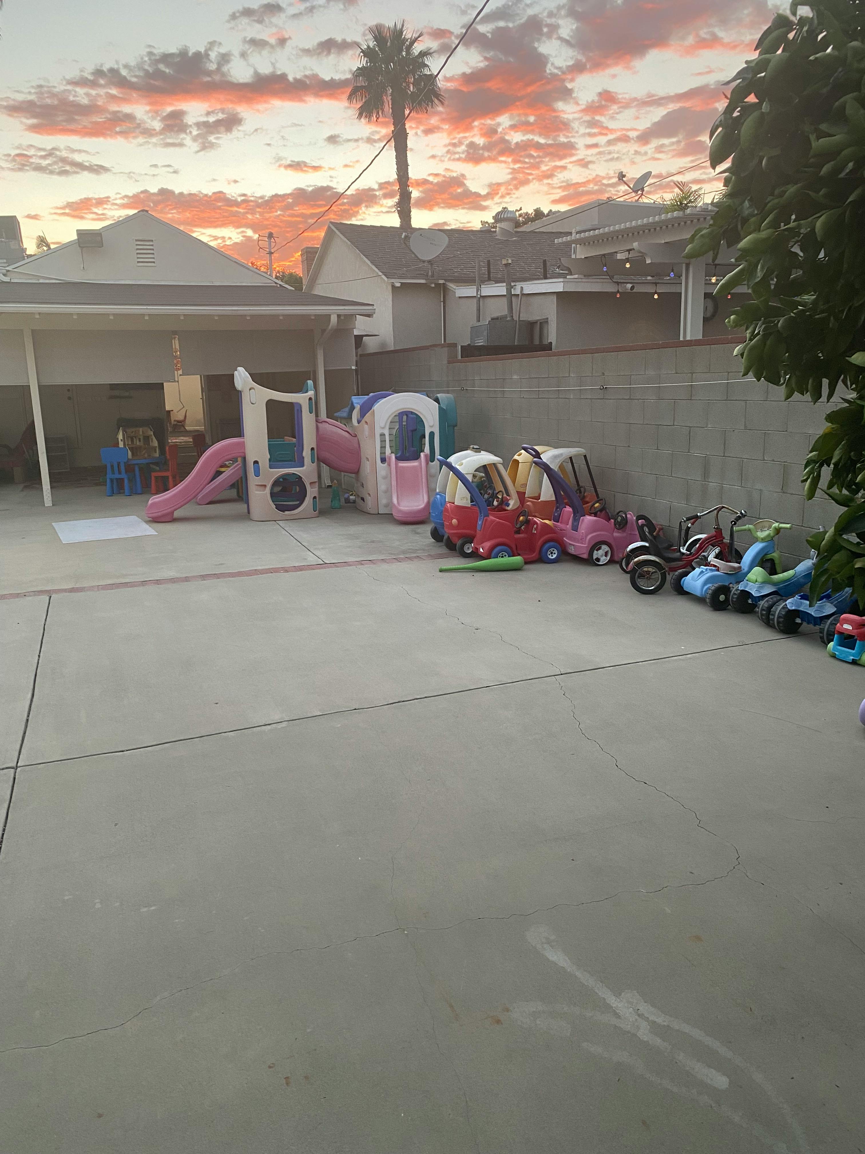 Playground with slides and ride-on toys under a sunset sky