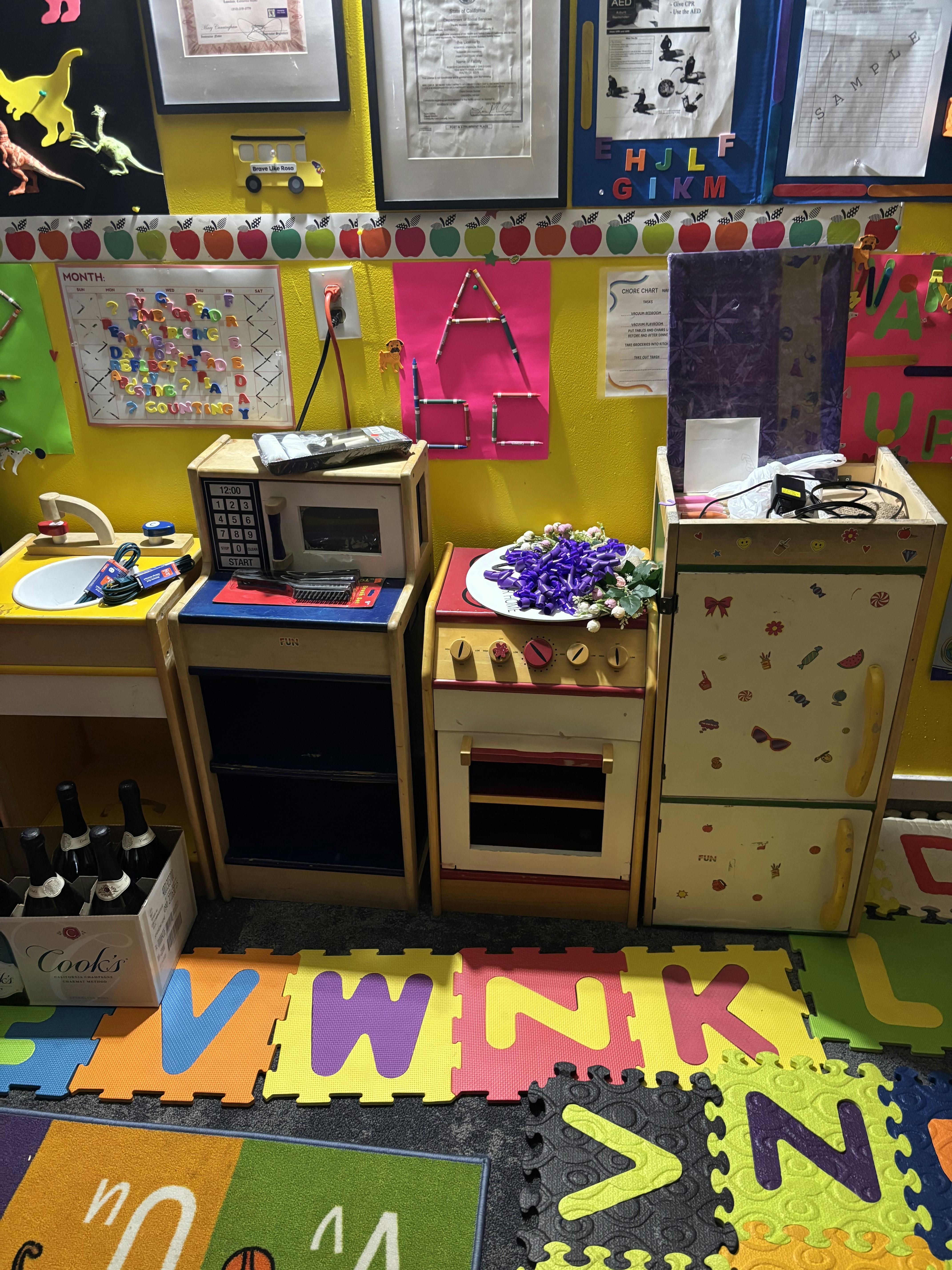 Toy kitchen set with play appliances on a letter-patterned floor mat