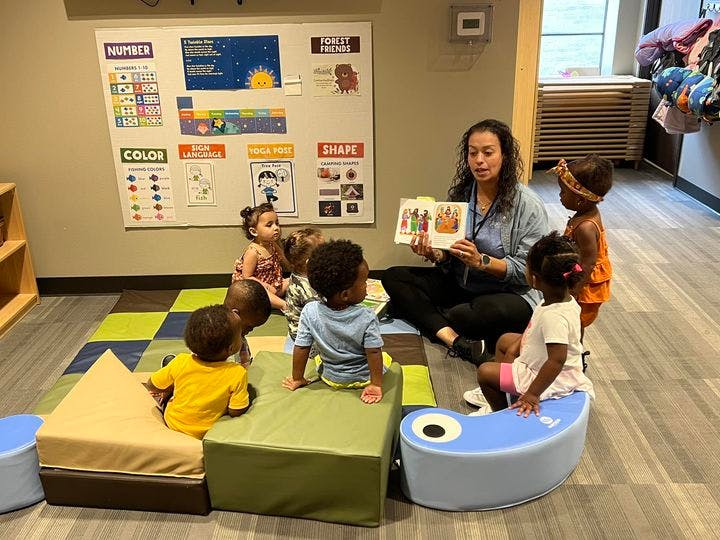 Person reading a book to a group of children in a classroom