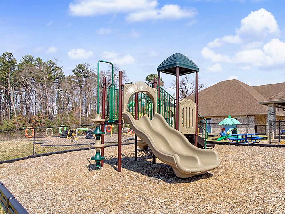 An empty outdoor playground with a large slide structure and wood chip ground