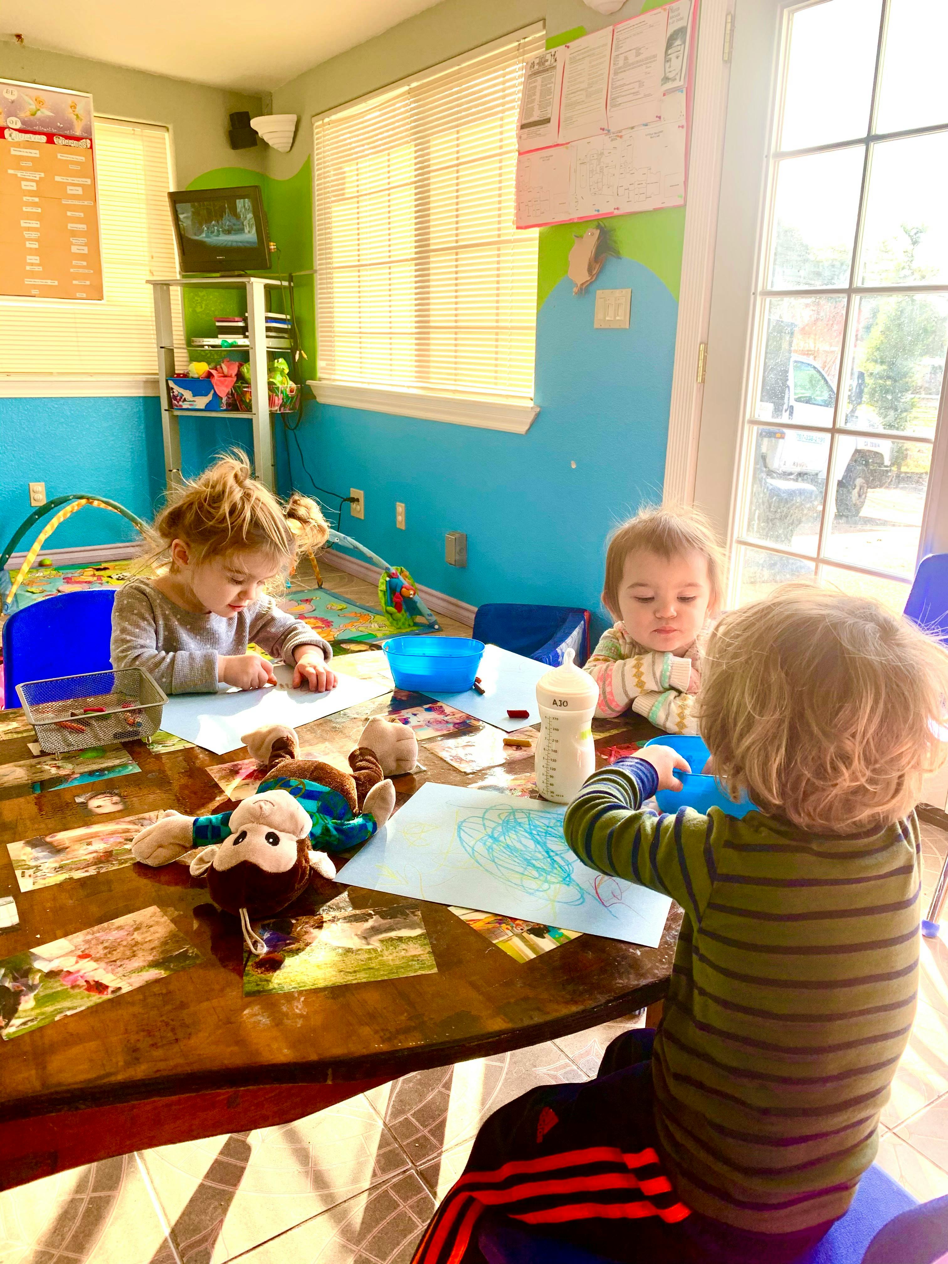 Three children drawing at a table