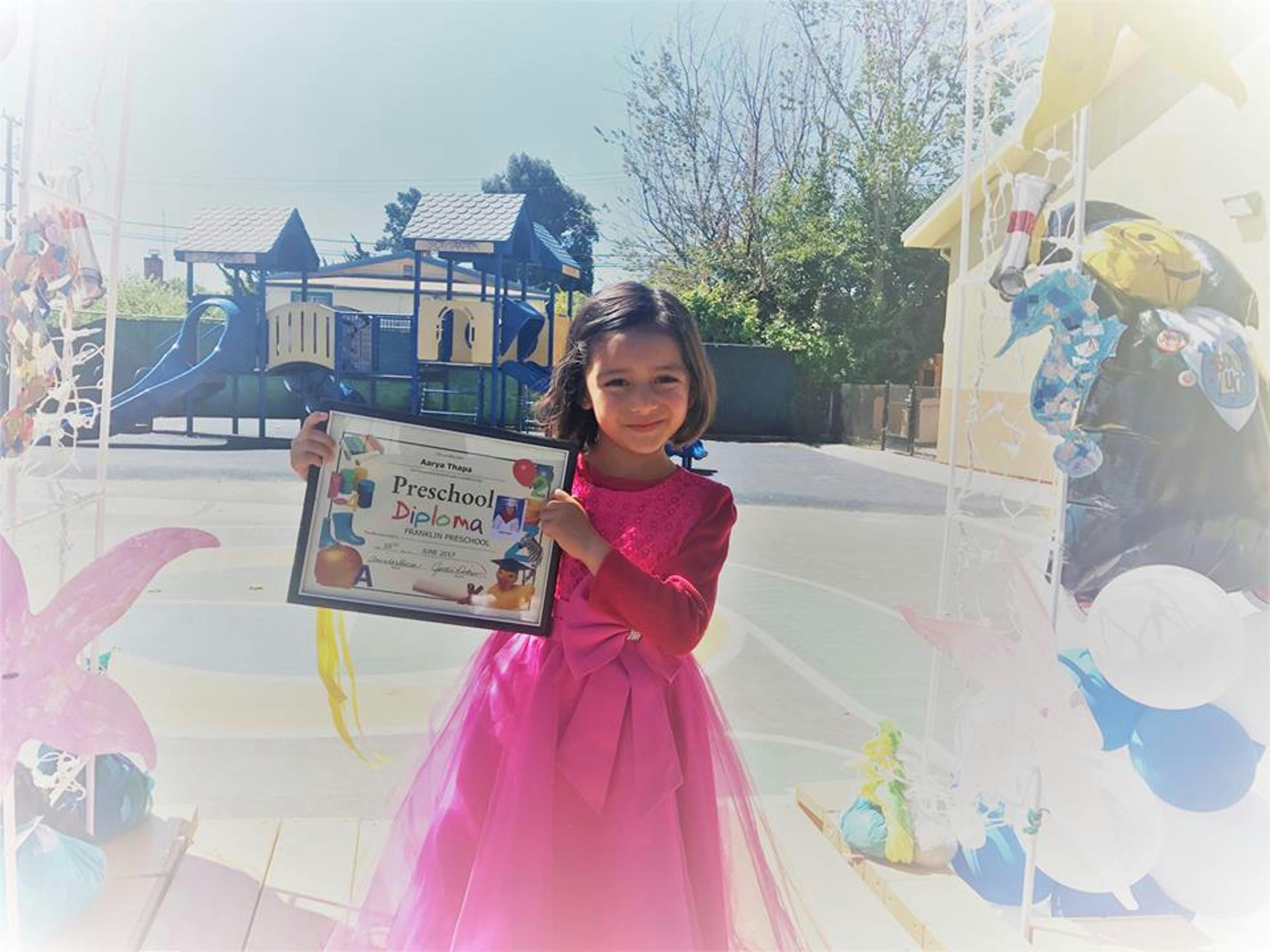 Child holding up a framed certificate outdoors