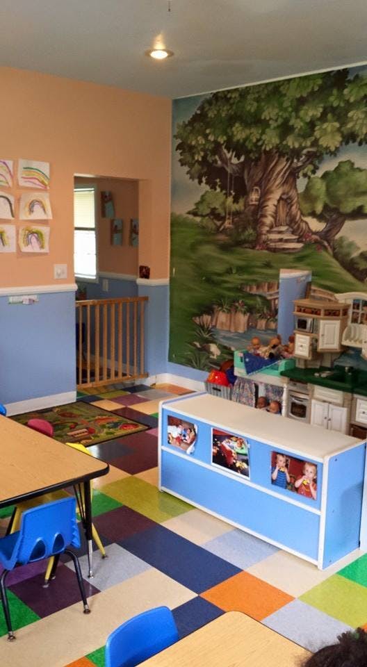 Classroom with colorful floor, tables, chairs, and a tree mural