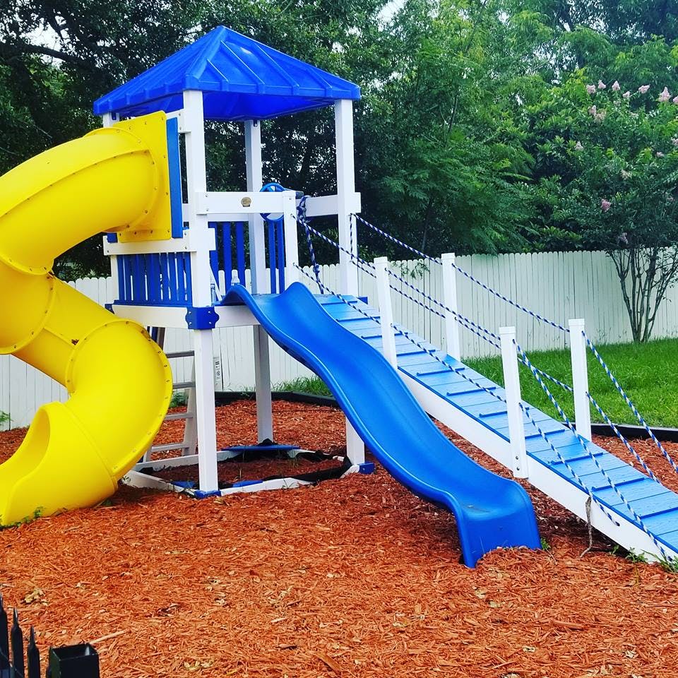 Playground with yellow tube slide, blue slide, and bridge overpass