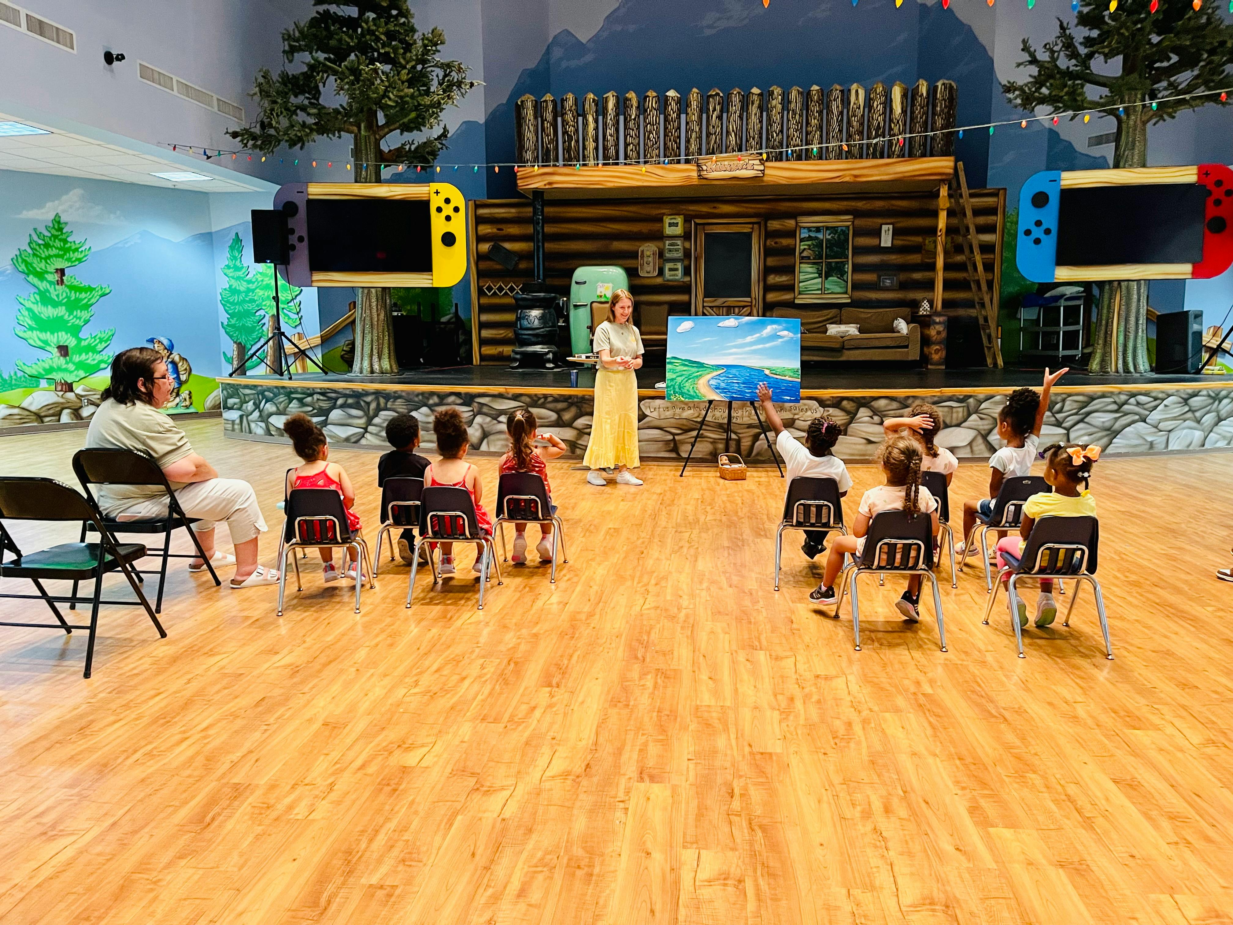 Adult teaching a group of children seated in chairs