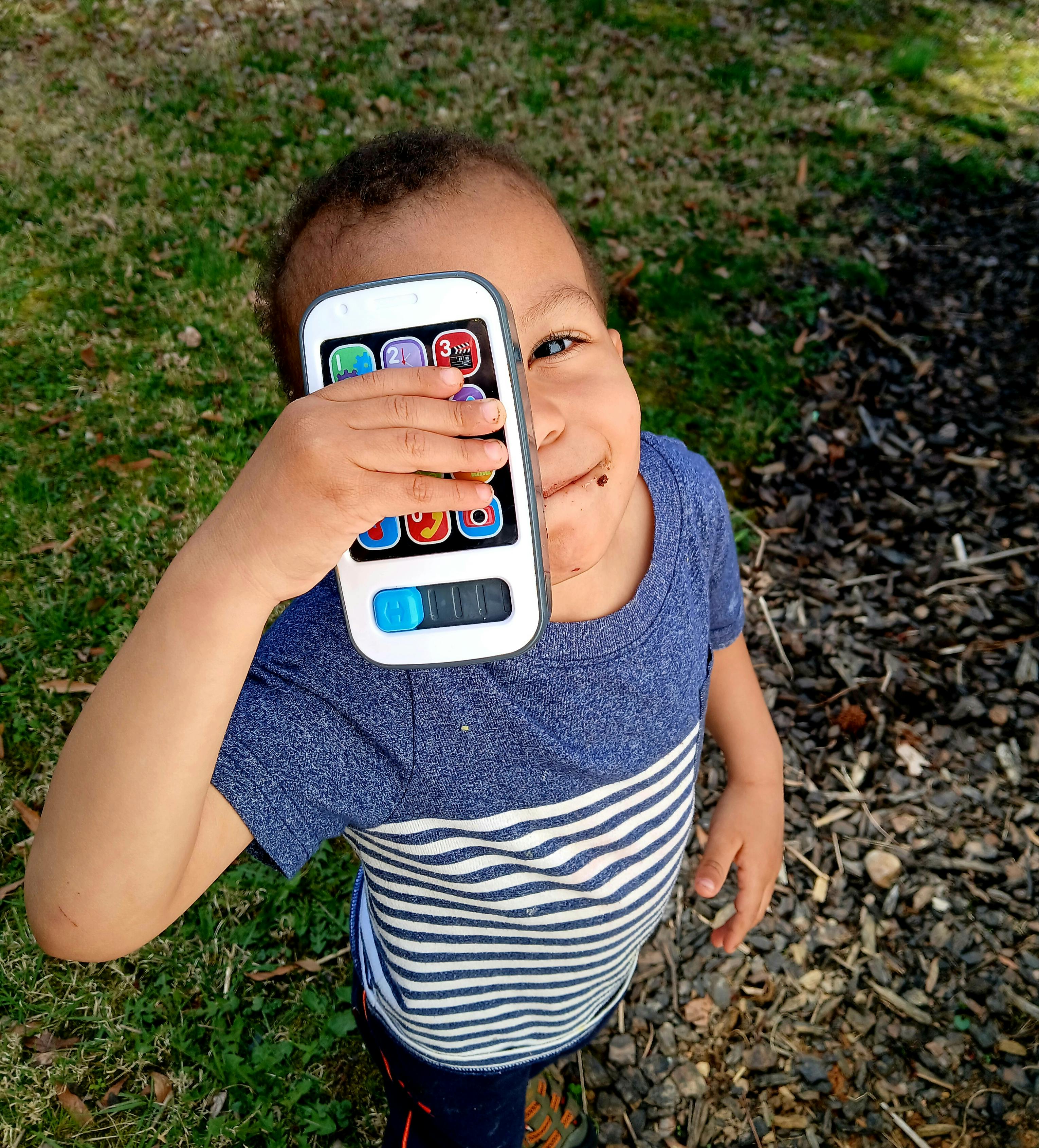 Child holding a toy phone over their face