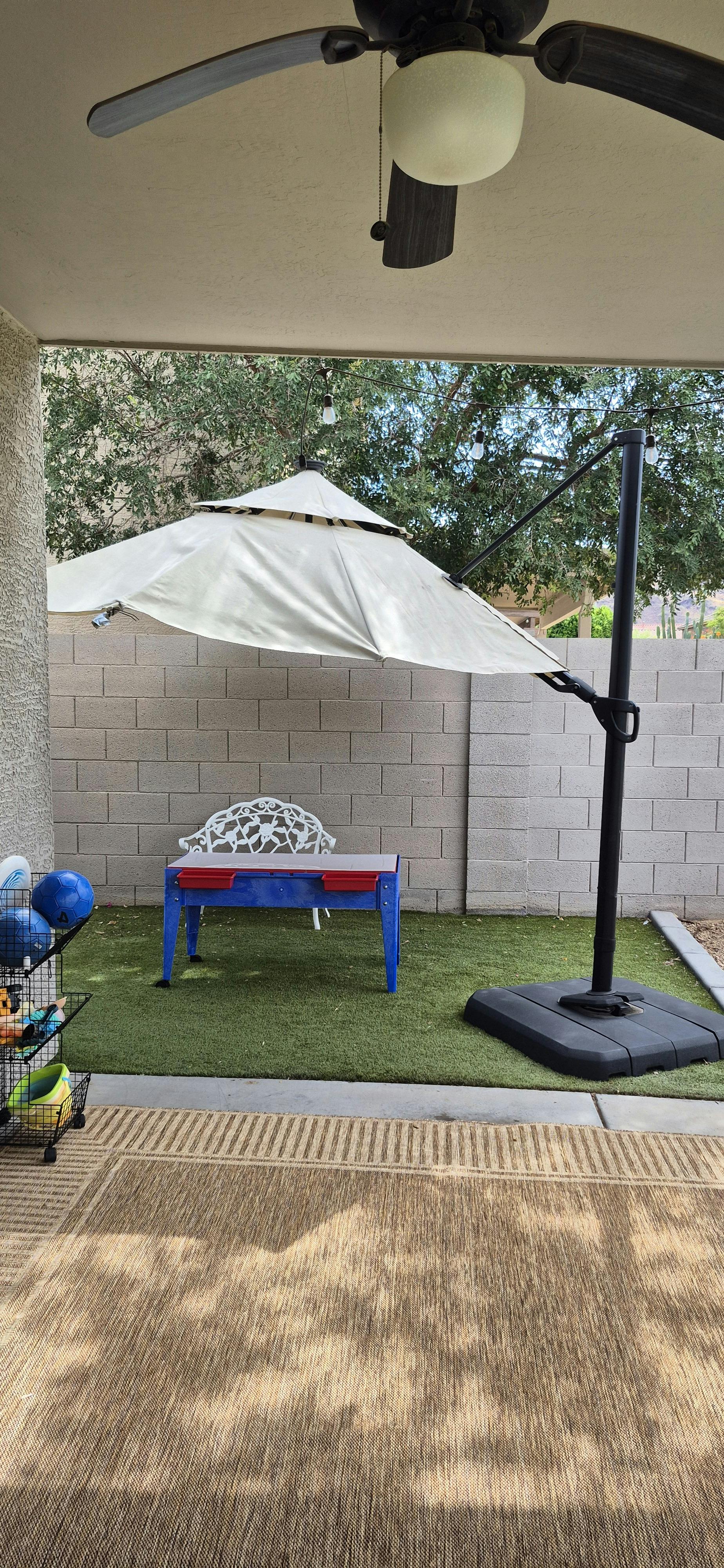Childs small table and chair under a patio umbrella on synthetic grass