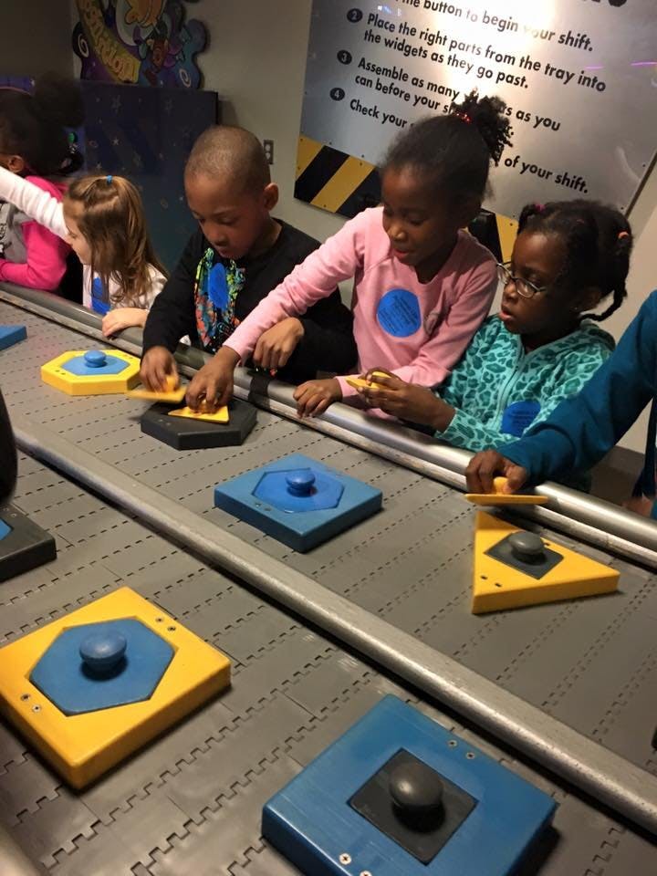 Children assembling parts on a moving conveyor belt