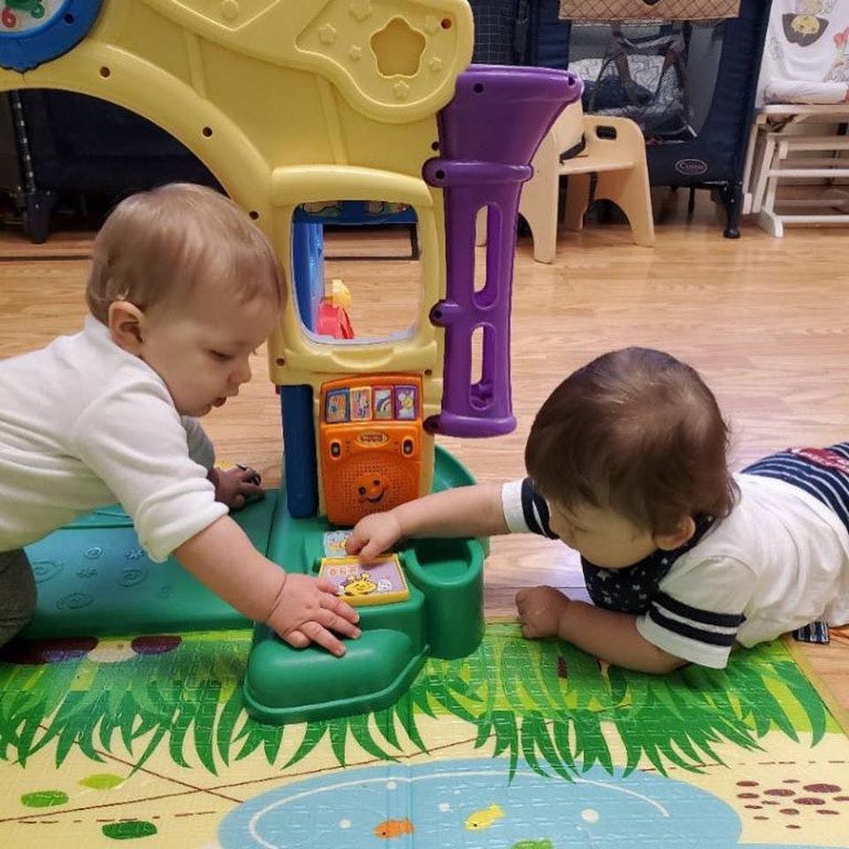 Two children playing with a colorful toy on a mat