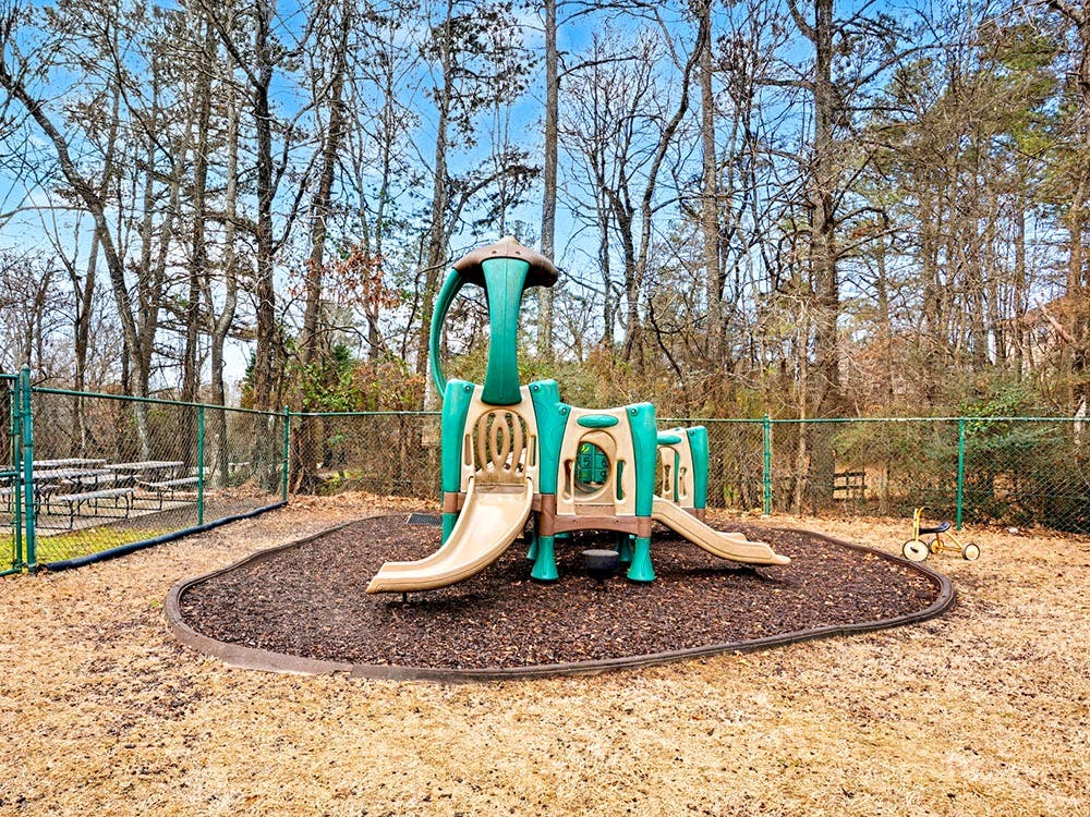 A small playground with a slide and climbing structure on wood chips