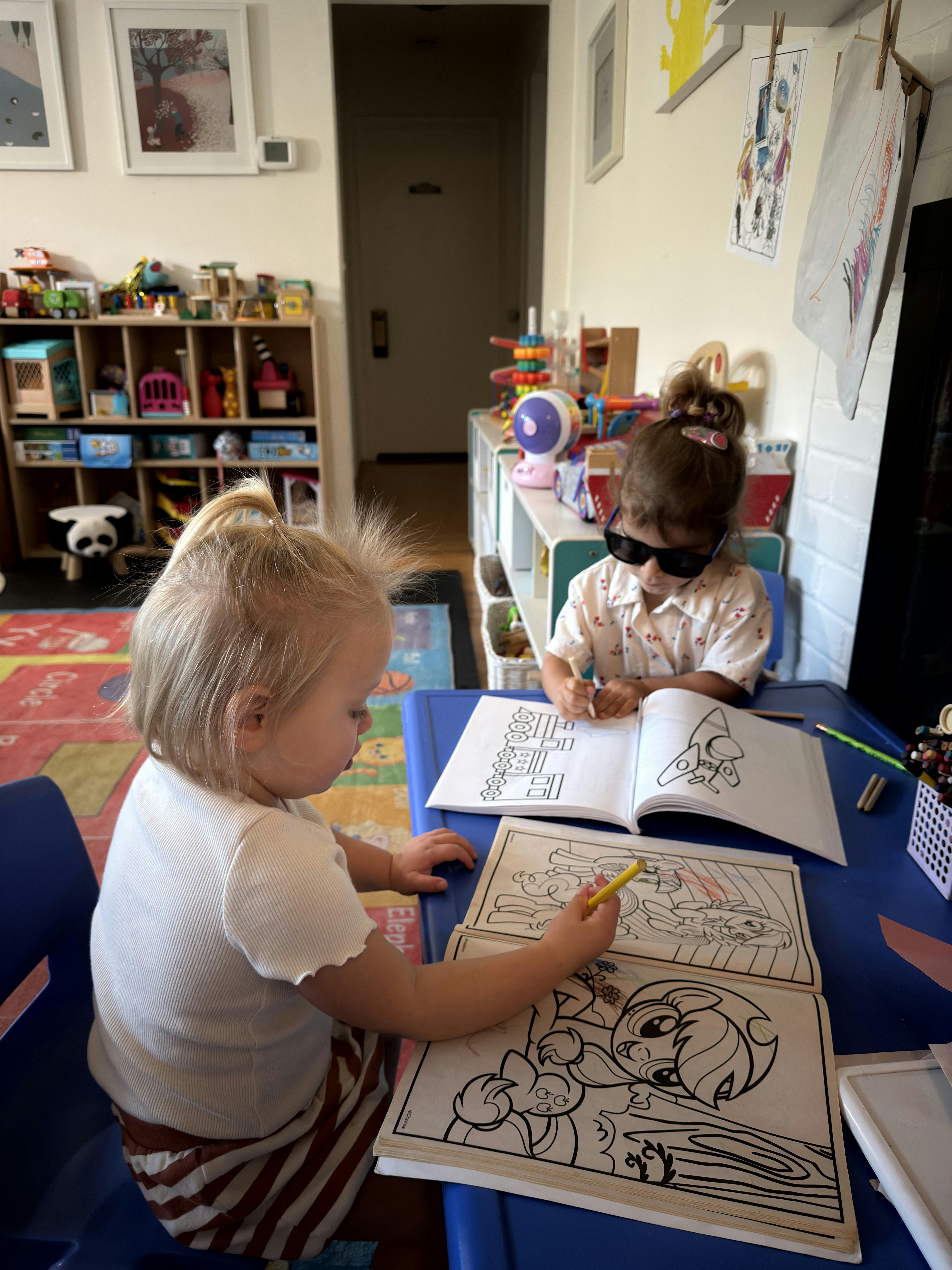 Two children coloring in books at a table