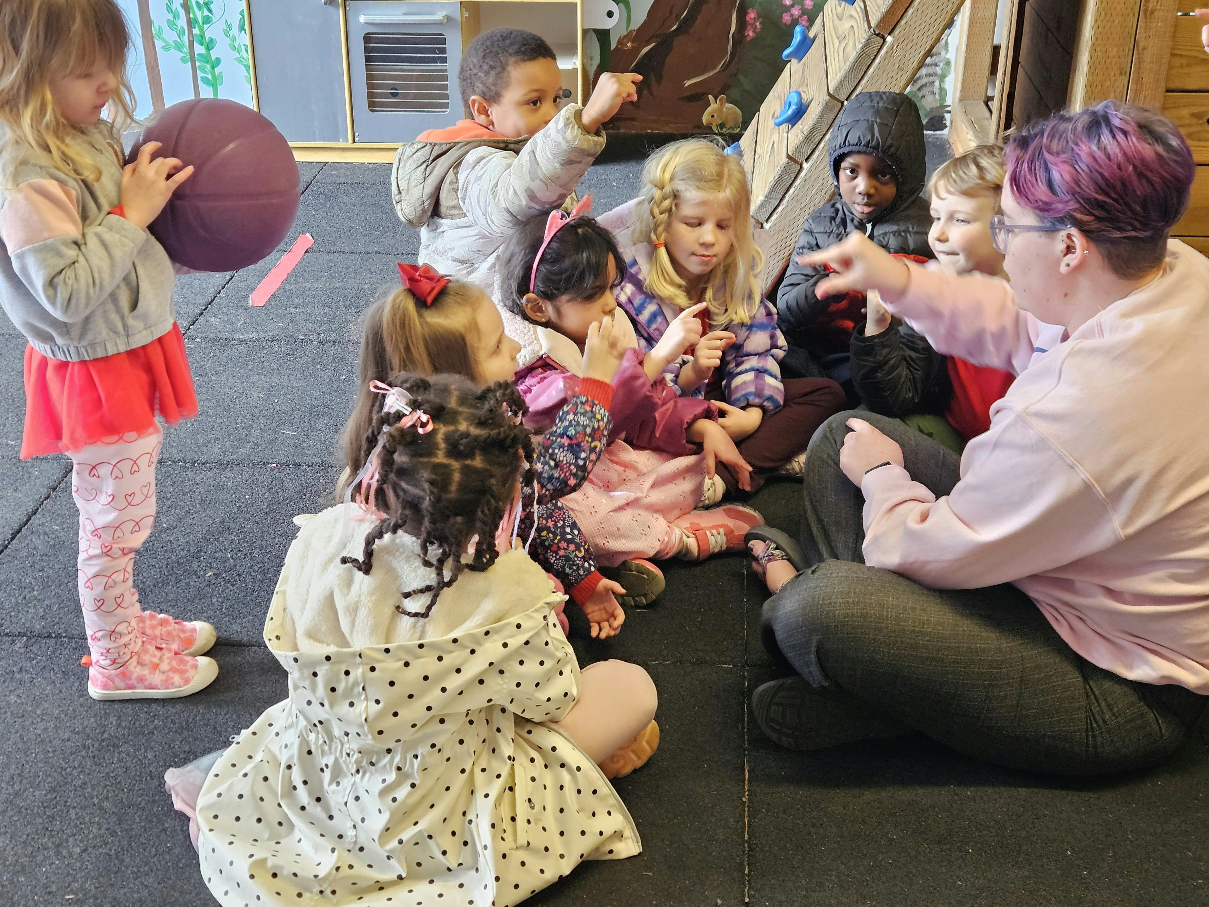 Adult and children sitting on floor, adult pointing