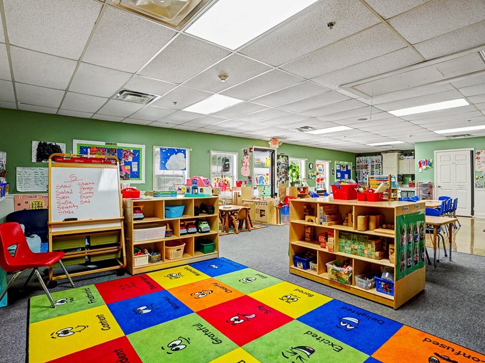 Colorful rug on the floor of an empty classroom with various shelves and a whiteboard