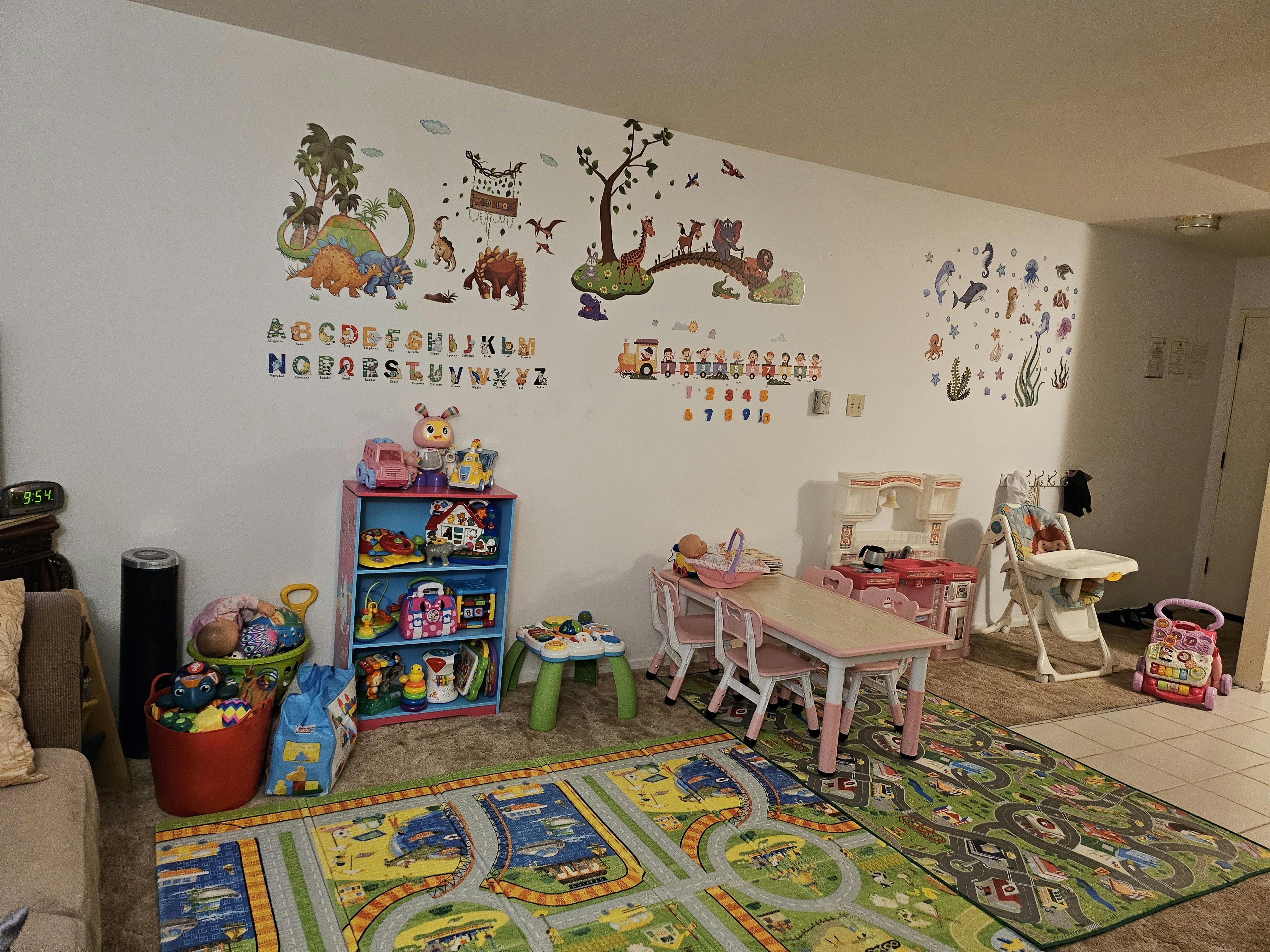 Playroom with wall decals, toy shelf, small table and chairs, and play mats