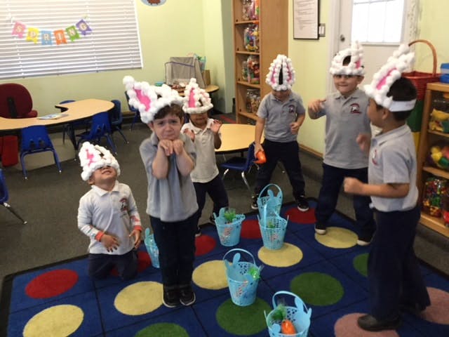 Children in bunny hats playing a game with baskets in a classroom
