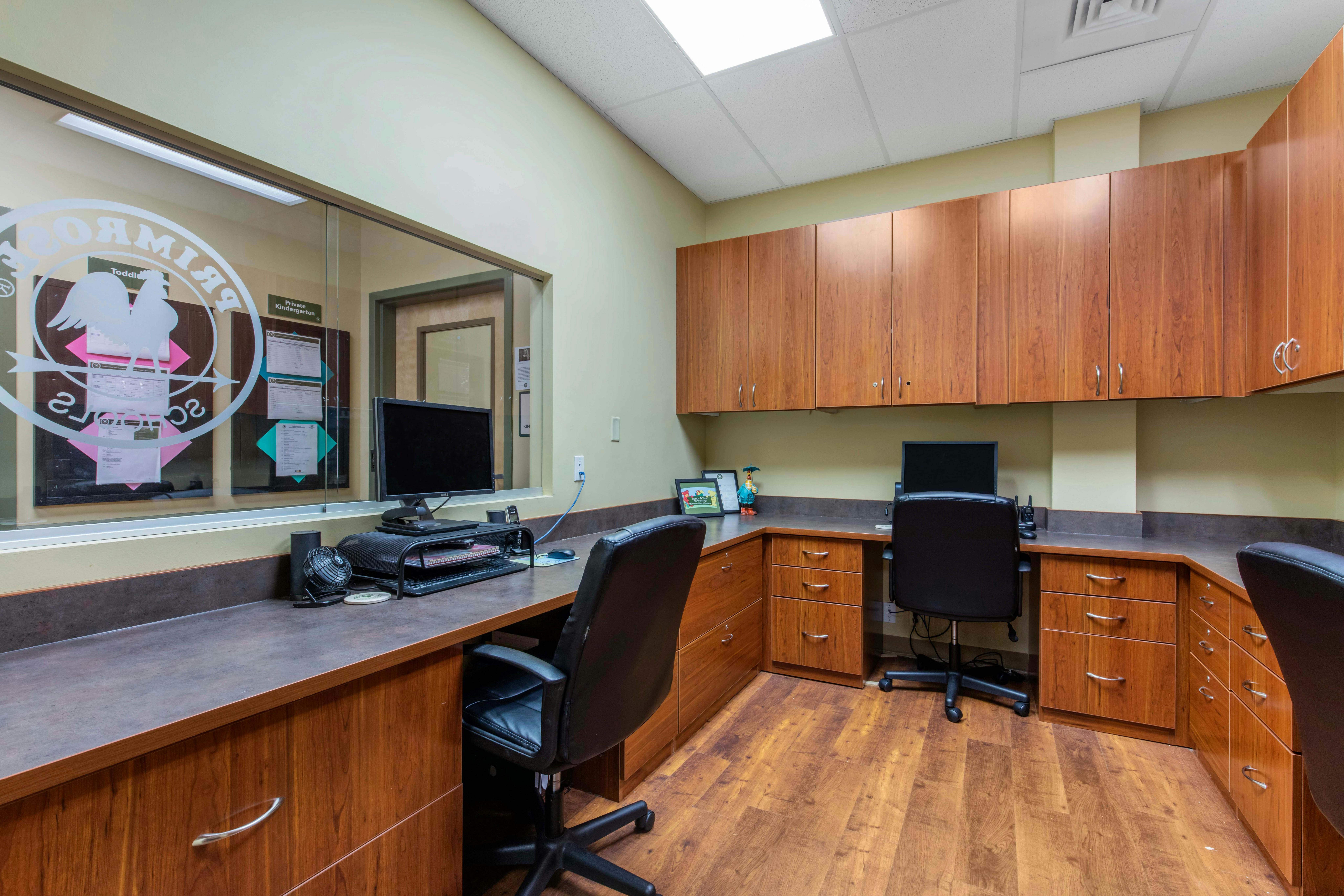 Office space with two computer workstations, chairs, and wood cabinets