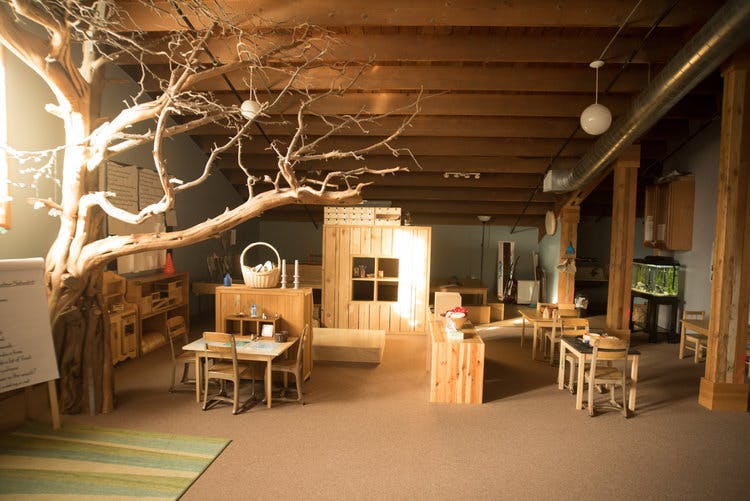 Indoor play area with wooden furniture and a large tree sculpture