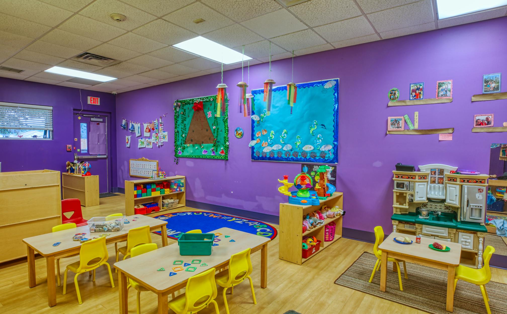 Colorful classroom with small tables and chairs, toys, and decorated walls